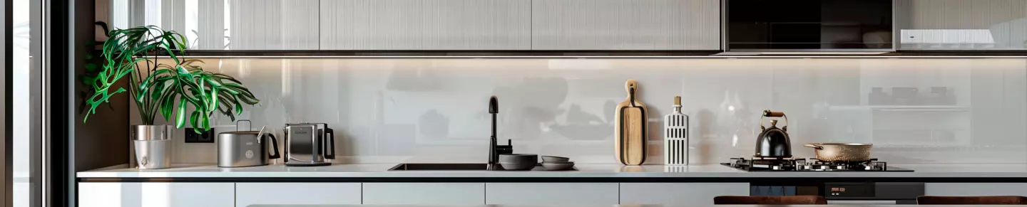 Helle, moderne Küche mit Toaster, Wasserkocher, Topfpflanze und Kochutensilien auf einer Arbeitsplatte.