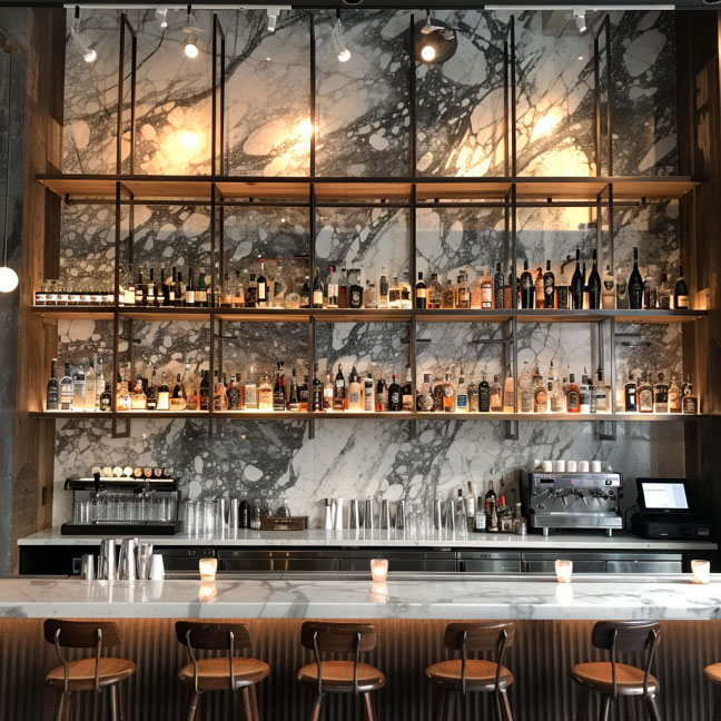 Moderne Bar mit Marmorrückwand und Regalen voller Flaschen Innenansicht einer stilvollen Bar mit Marmorrückwand, hohen Regalen mit verschiedenen Spirituosenflaschen und gemütlichen Barhockern.