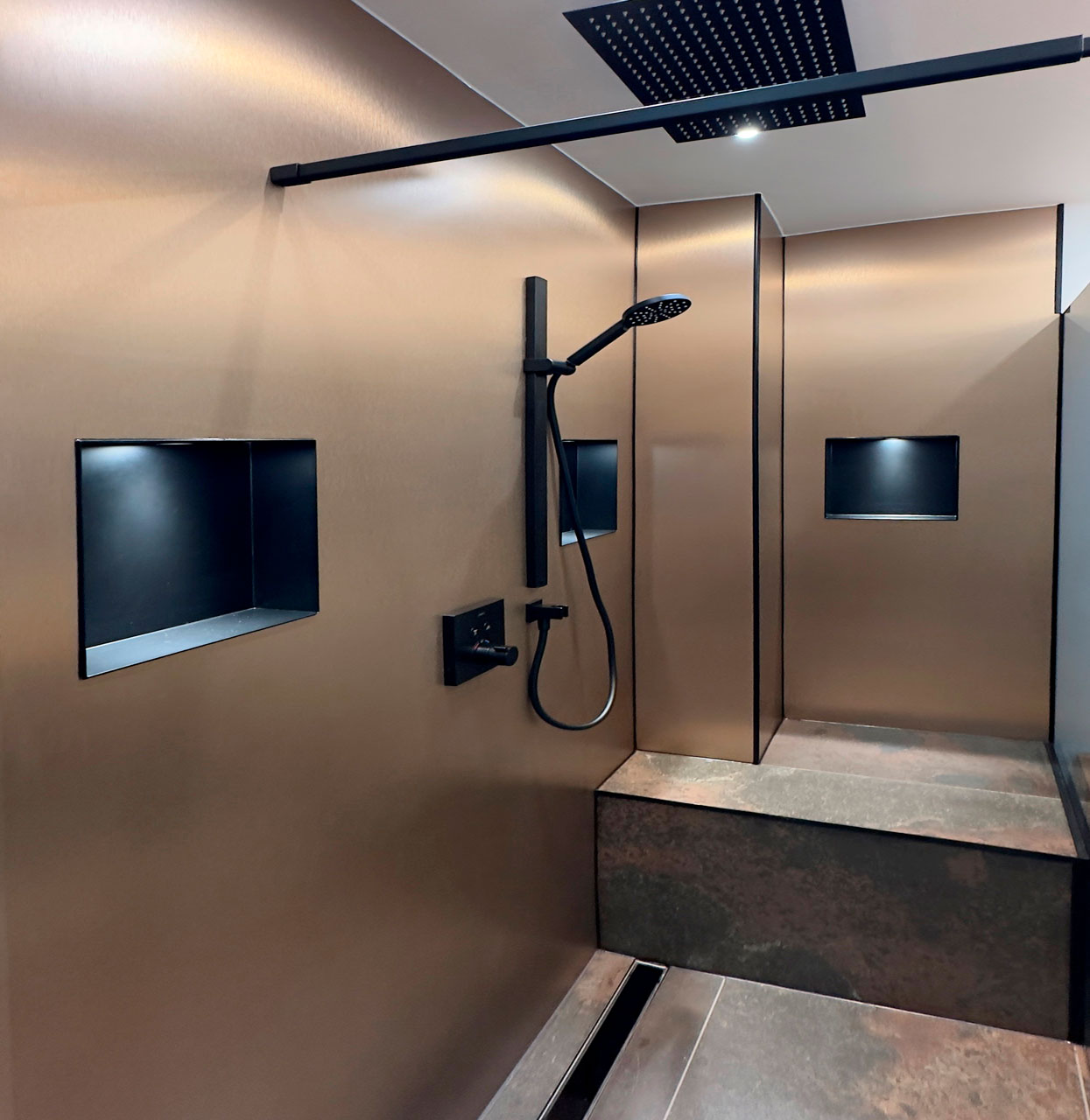 Moderne Dusche mit Wandnischen und Regenduschkopf Elegante, moderne Dusche mit bronzeähnlichen Wänden, Regenduschkopf und integrierten Nischen für Duschutensilien